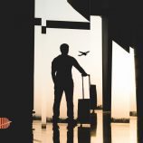 A man standing at the airport looking at planes signifying the relocation process to different tax jurisdictions